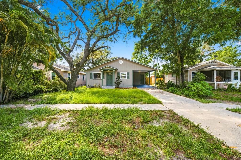 A single-story house with a carport and a front lawn shaded by large trees — 1528 S MADISON AVENUE, CLEARWATER, FL