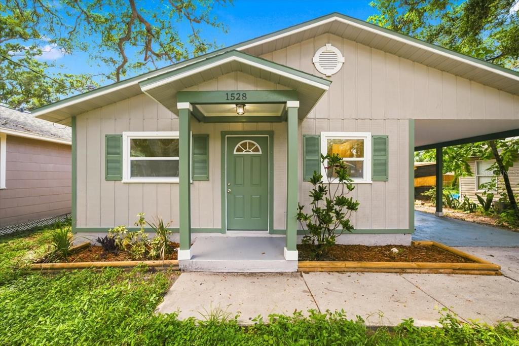A single-story house with light gray siding, green shutters, and a covered front porch entrance — 1528 S MADISON AVENUE, CLEARWATER, FL