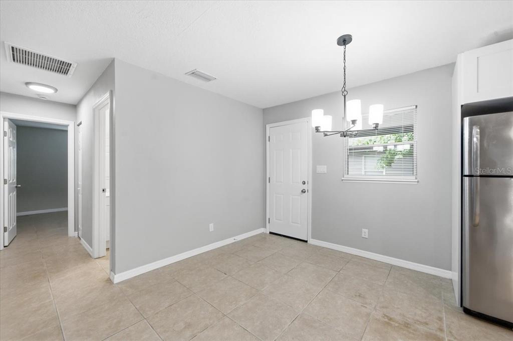 A dining area features light gray walls, tile flooring, a chandelier, and a white door — 1528 S MADISON AVENUE, CLEARWATER, FL