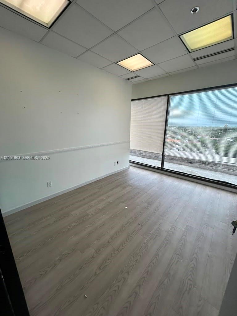 An empty office with light wood-look flooring, white walls, and a large window with blinds — 900 W 49th St Suite 524, Hialeah FL 33012, HIALEAH, FL