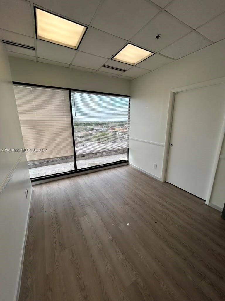 An office room features wood-look flooring, a large window with blinds, and a drop ceiling — 900 W 49th St Suite 524, Hialeah FL 33012, HIALEAH, FL