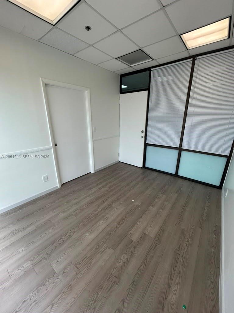An empty office features light wood-look flooring, white walls, and a glass-paneled wall partition — 900 W 49th St Suite 524, Hialeah FL 33012, HIALEAH, FL