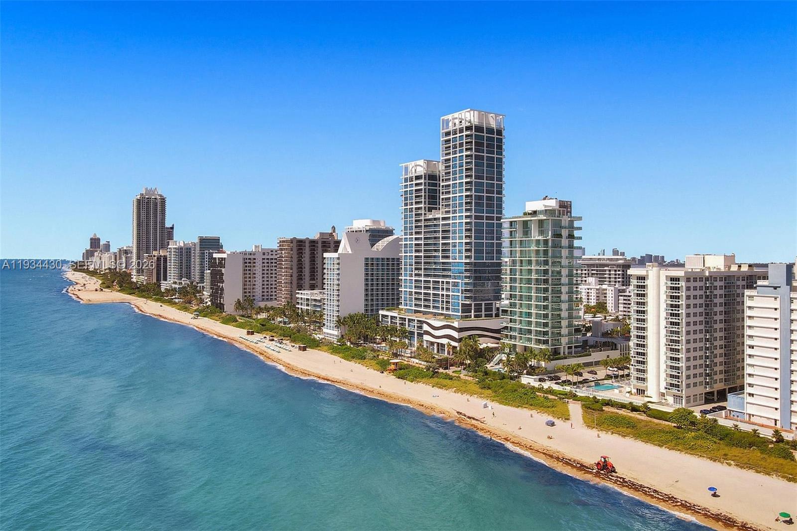 An aerial view shows a sandy beach lined with high-rise buildings along the ocean — 6917 Collins Ave # 503, Miami Beach FL 33141, MIAMI BEACH, FL