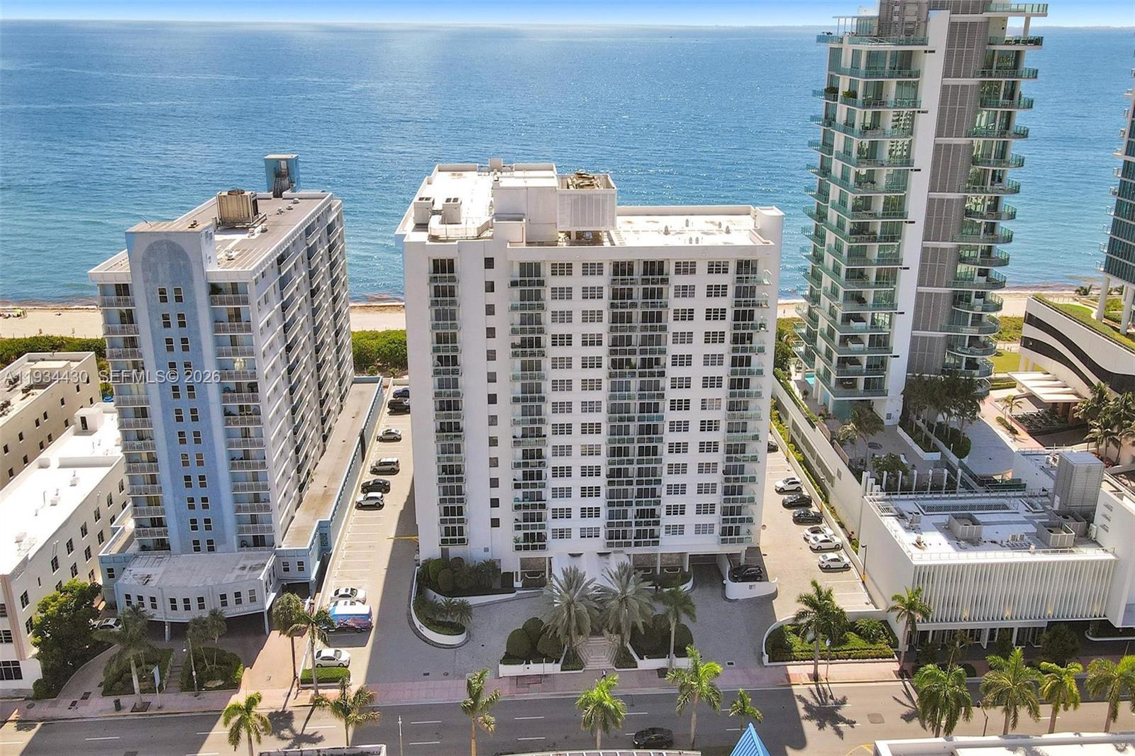 An aerial view shows three high-rise residential buildings situated along a sandy beach — 6917 Collins Ave # 503, Miami Beach FL 33141, MIAMI BEACH, FL