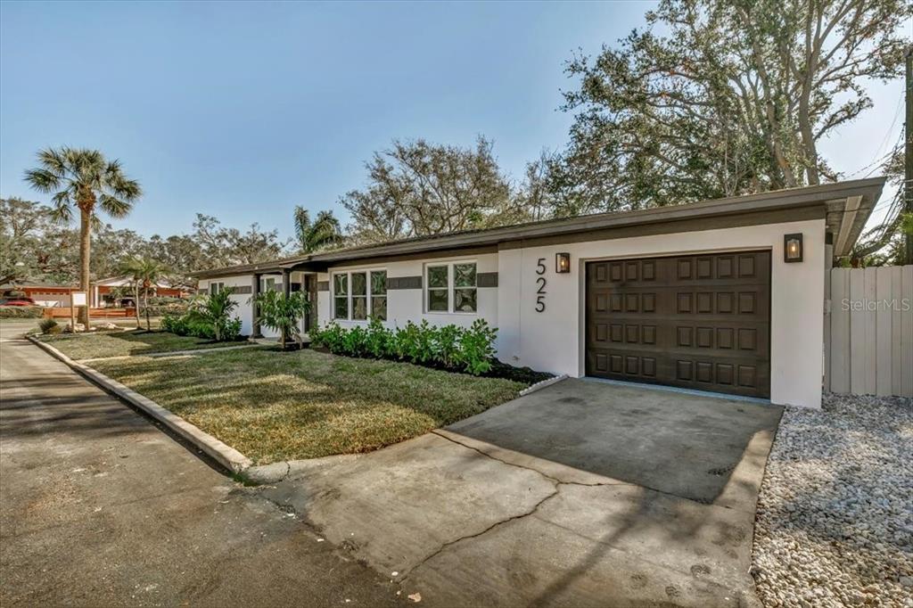 A single-story house with a white exterior, dark garage door, and a front lawn — 525 LAMARA WAY NE, ST PETERSBURG, FL