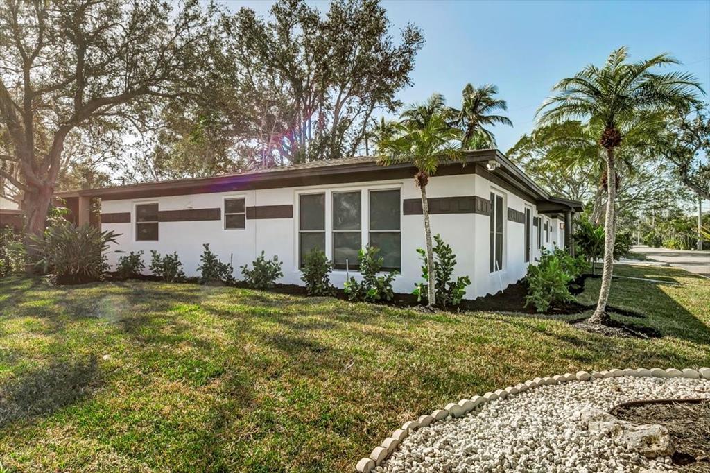 A single-story white house with dark trim sits on a lawn with palm trees — 525 LAMARA WAY NE, ST PETERSBURG, FL