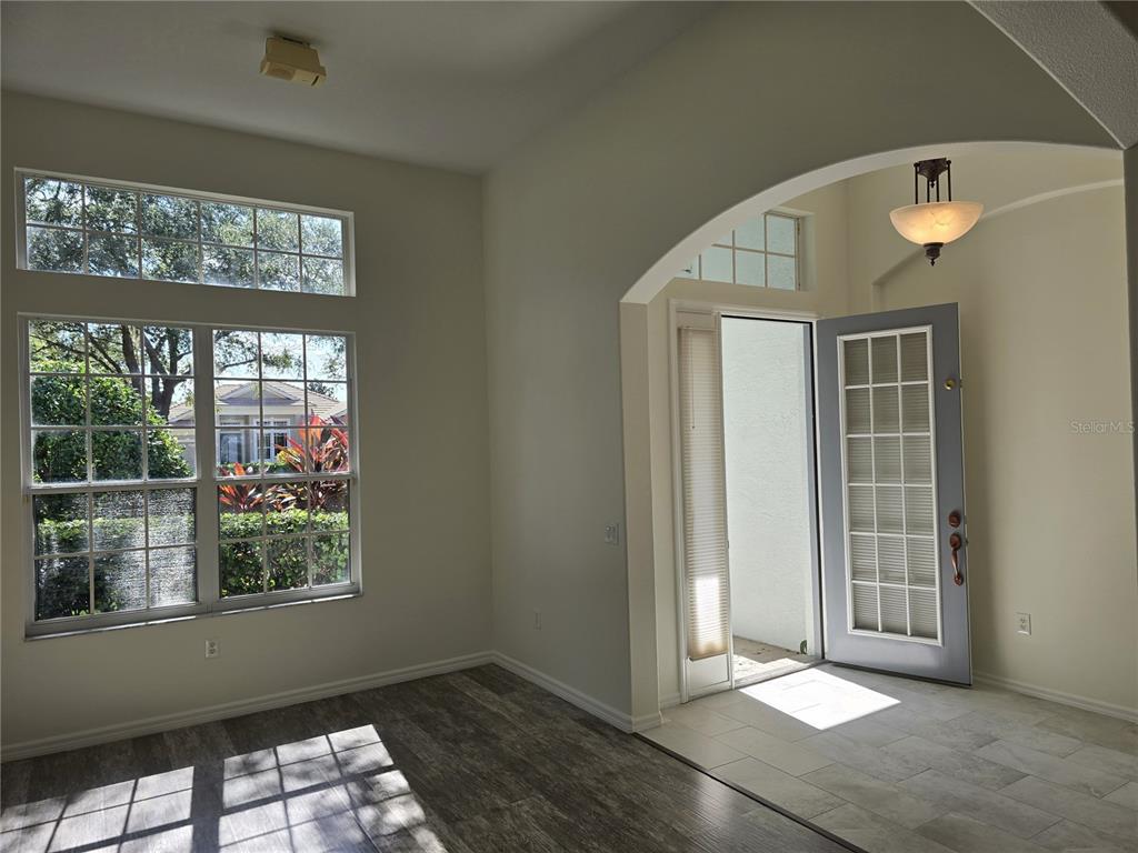A room with wood-look flooring, a tiled entryway, and a front door with glass panels — 8427 SAILING LOOP, LAKEWOOD RANCH, FL