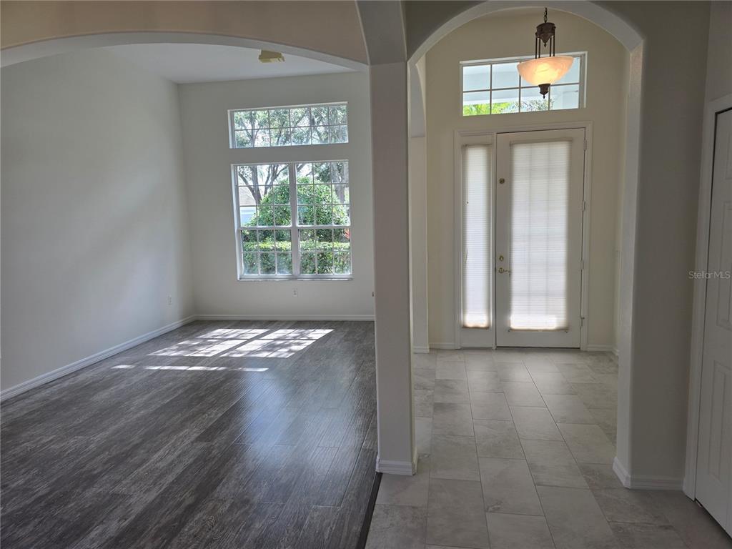 An entryway with tile flooring leads into a living area featuring wood-look flooring and windows — 8427 SAILING LOOP, LAKEWOOD RANCH, FL