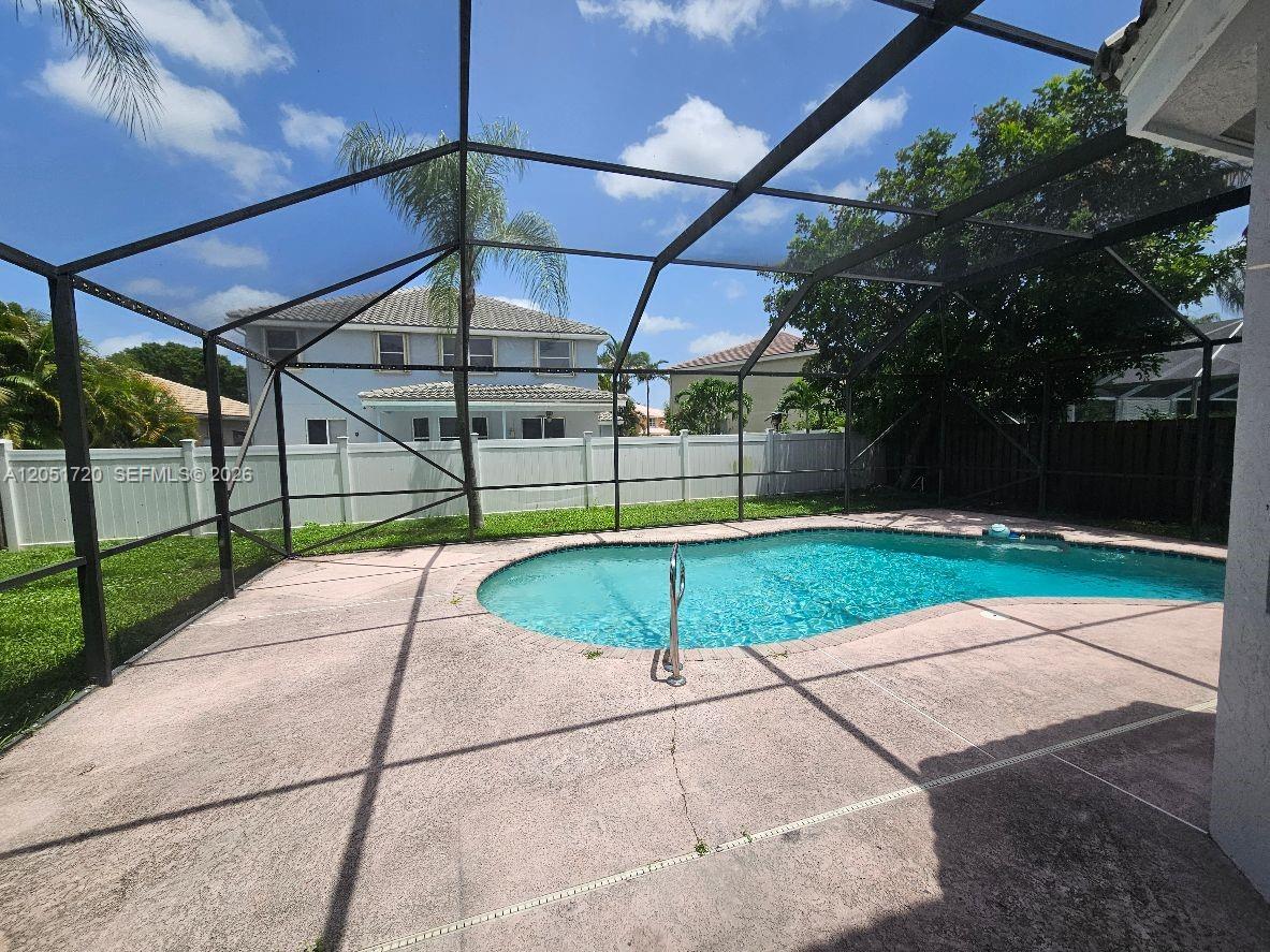 A screened-in patio features a swimming pool and concrete deck enclosed by a white fence — 7558 Prescott Ln, Lake Worth FL 33467, LAKE WORTH, FL
