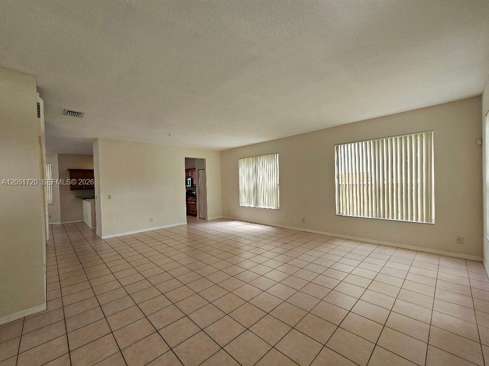 An empty living room features beige walls and light-colored tile flooring — 7558 Prescott Ln, Lake Worth FL 33467, LAKE WORTH, FL
