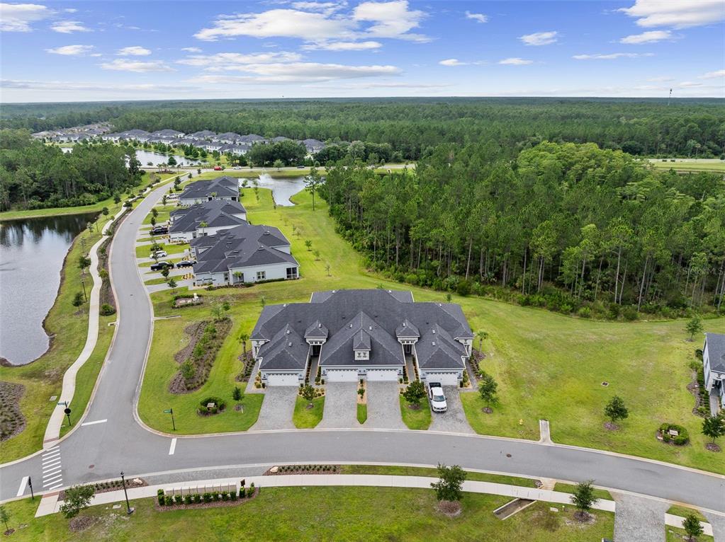 An aerial view shows a multi-unit residential building with a dark roof and paved driveways — 7 NEWHAVEN LANE, ORMOND BEACH, FL