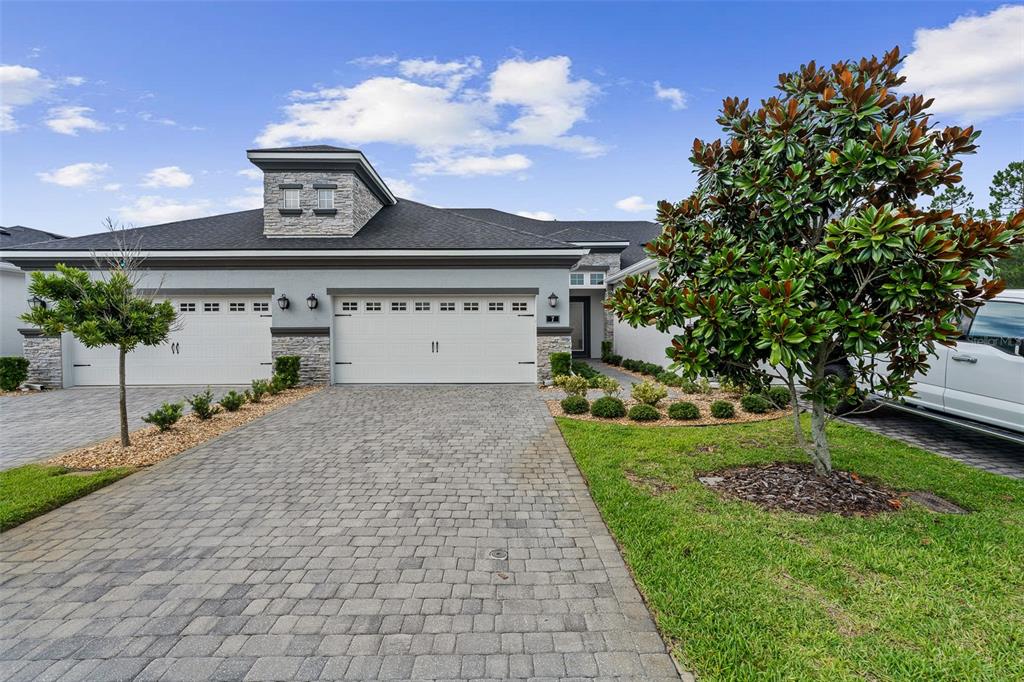 A single-story house with a stone-accented facade, a three-car garage, and a paved driveway — 7 NEWHAVEN LANE, ORMOND BEACH, FL