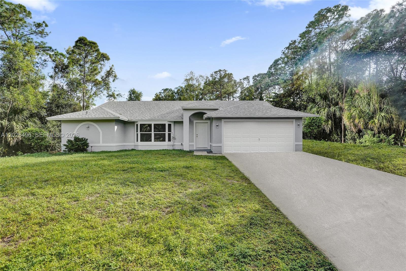 A single-story house with a white garage, gray roof, and a grassy front yard — 14808 N 69th St N, Loxahatchee FL 33470, LOXAHATCHEE, FL