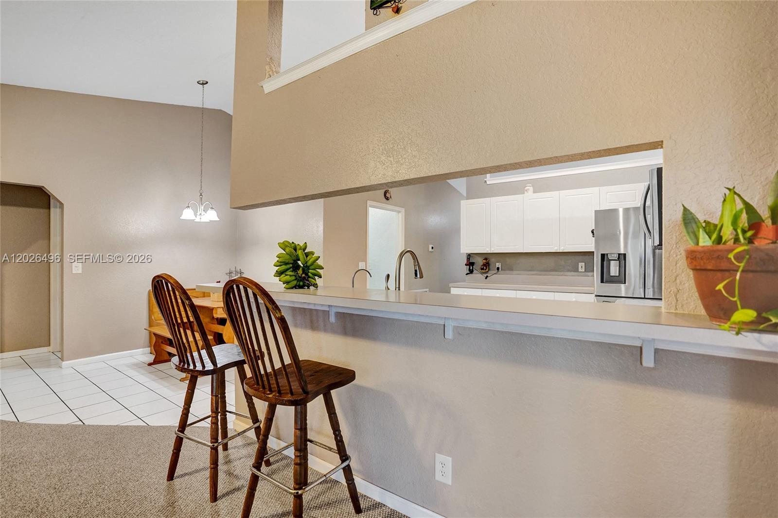 A kitchen with white cabinets and a breakfast bar overlooks a dining area — 14808 N 69th St N, Loxahatchee FL 33470, LOXAHATCHEE, FL