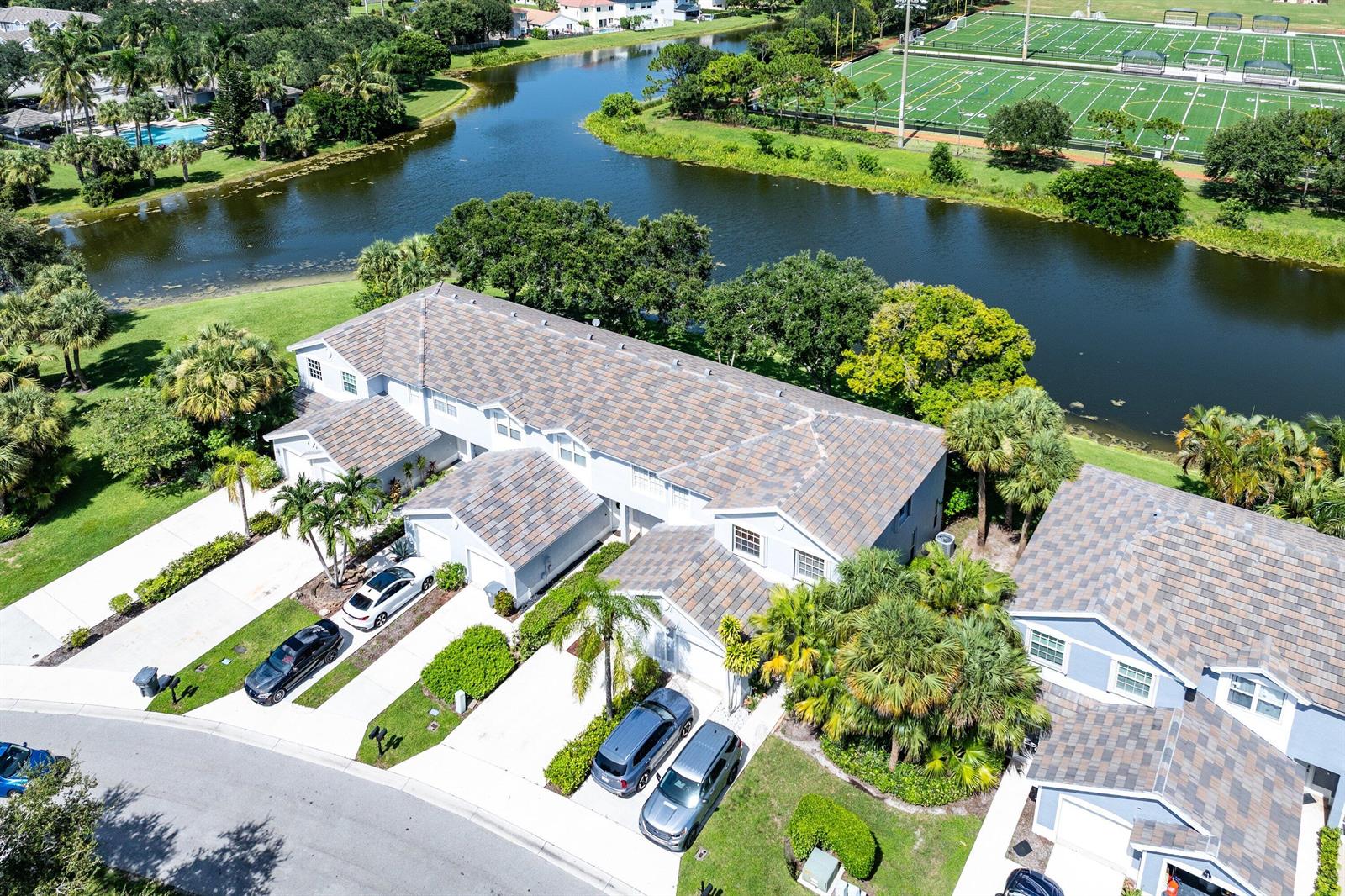 An aerial view shows a multi-unit residential building with tiled roofs near a canal — 7874 Sienna Springs Drive, Lake Worth FL 33463, LAKE WORTH, FL