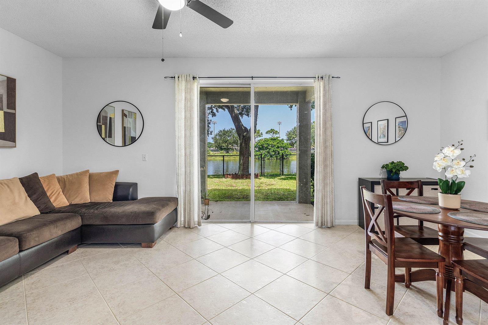 A living and dining area with tile floors, a sectional sofa, and sliding glass doors — 7874 Sienna Springs Drive, Lake Worth FL 33463, LAKE WORTH, FL