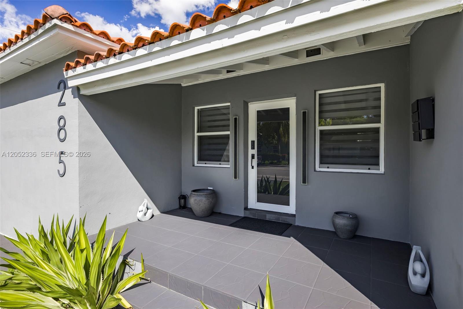 The exterior entrance features a gray tiled porch, a glass door, and terracotta roof tiles — 285 NW 45th St # 0, Miami FL 33127, MIAMI, FL