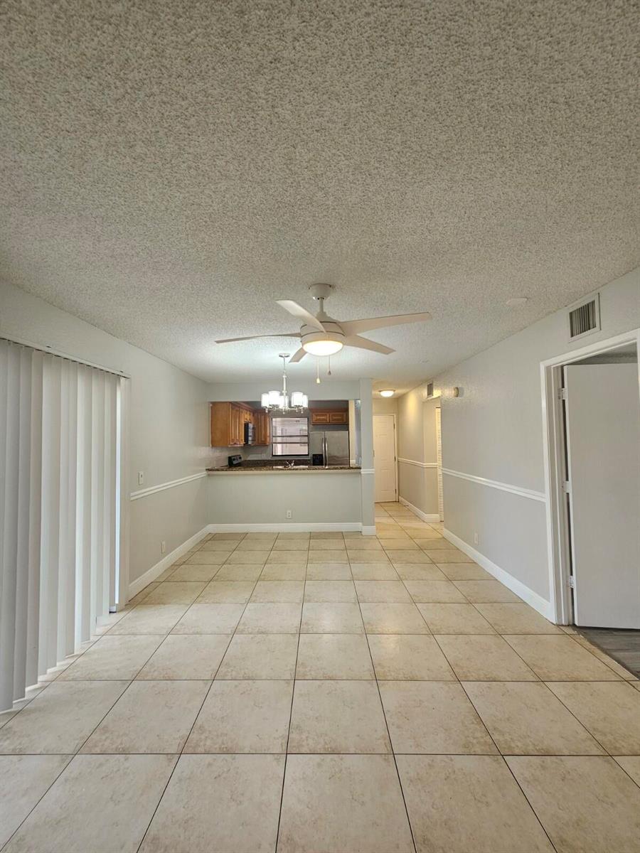 A dining area with tile flooring, a ceiling fan, and a pass-through to the kitchen — 1700 Windorah Way # A, West Palm Beach FL 33411, WEST PALM BEACH, FL