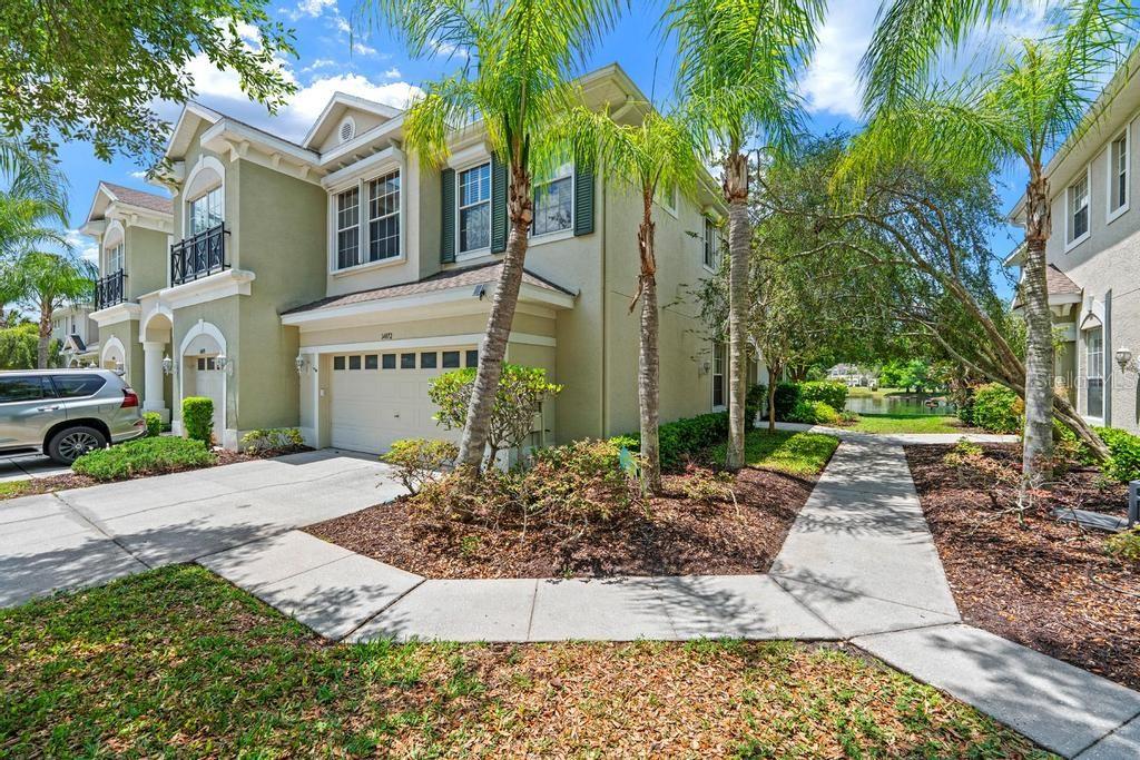 A two-story tan house with a garage, palm trees, and a concrete walkway — 14072 WATERVILLE CIRCLE, TAMPA, FL