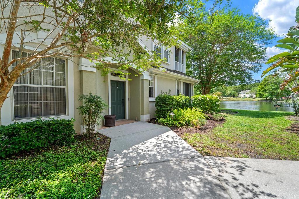 A concrete walkway leads to the front entrance of a two-story home near a pond — 14072 WATERVILLE CIRCLE, TAMPA, FL