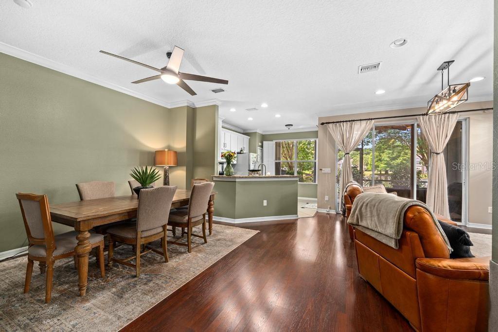 An open-concept dining and living area features hardwood floors, a ceiling fan, and sliding doors — 14072 WATERVILLE CIRCLE, TAMPA, FL