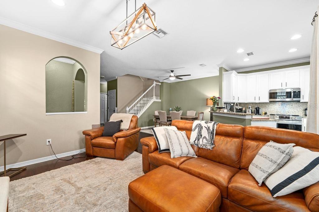 A living room with a leather sofa and armchair, hardwood floors, and an open kitchen — 14072 WATERVILLE CIRCLE, TAMPA, FL