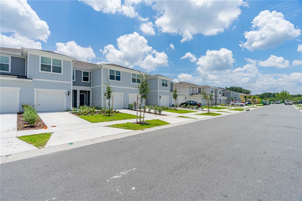 A row of light blue townhouses with attached garages lines a suburban street under a cloudy sky — 2609 BRIGHT JEWEL STREET UNIT 2909, KISSIMMEE, FL