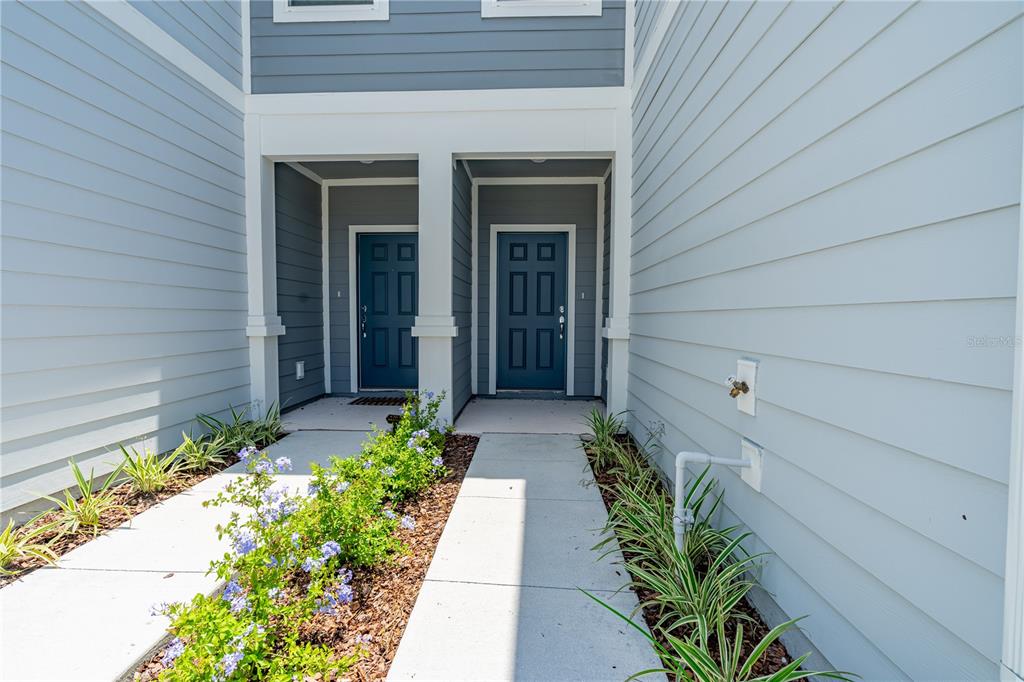 The exterior view shows two blue front doors with matching walkways and landscaped garden beds — 2609 BRIGHT JEWEL STREET UNIT 2909, KISSIMMEE, FL
