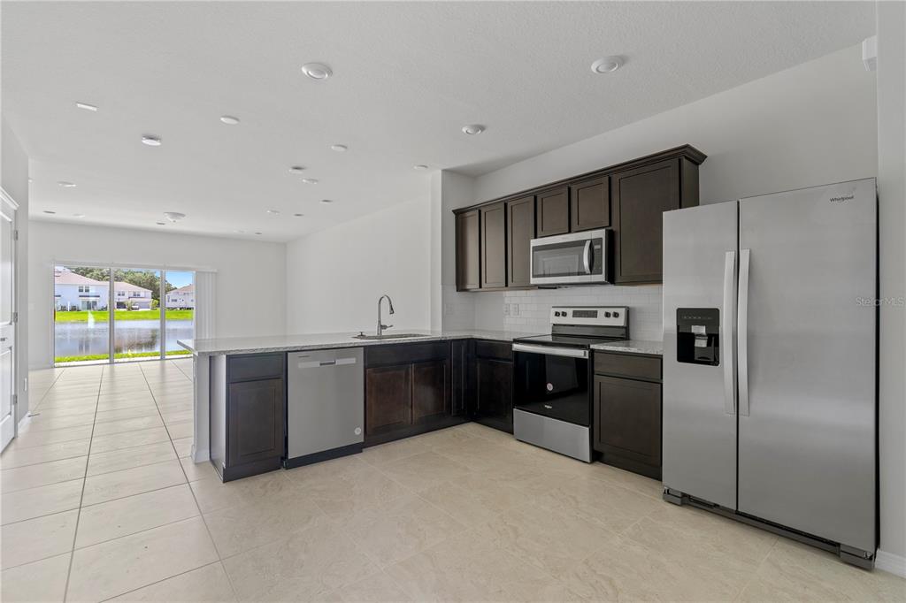 A kitchen features dark wood cabinets, stainless steel appliances, and a view of a pond — 2609 BRIGHT JEWEL STREET UNIT 2909, KISSIMMEE, FL