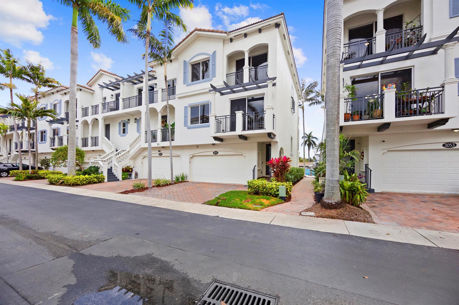 A street-level view of white multi-story townhouses with balconies, garages, and palm trees — 3055 Waterside Circle, Boynton Beach FL 33435, BOYNTON BEACH, FL