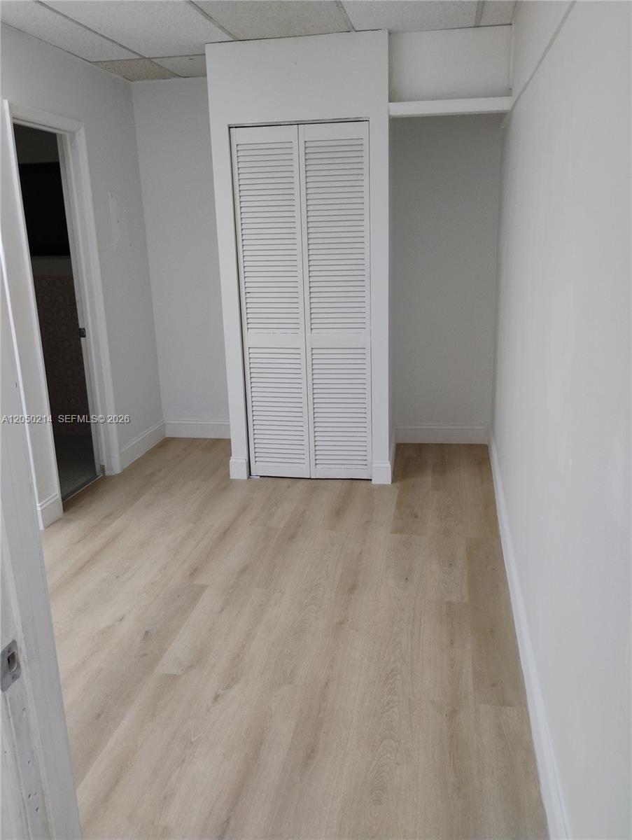 This room features light wood-look flooring, white walls, and a white louvered closet door — 285 NW 27th Ave # 9, Miami FL 33125, MIAMI, FL