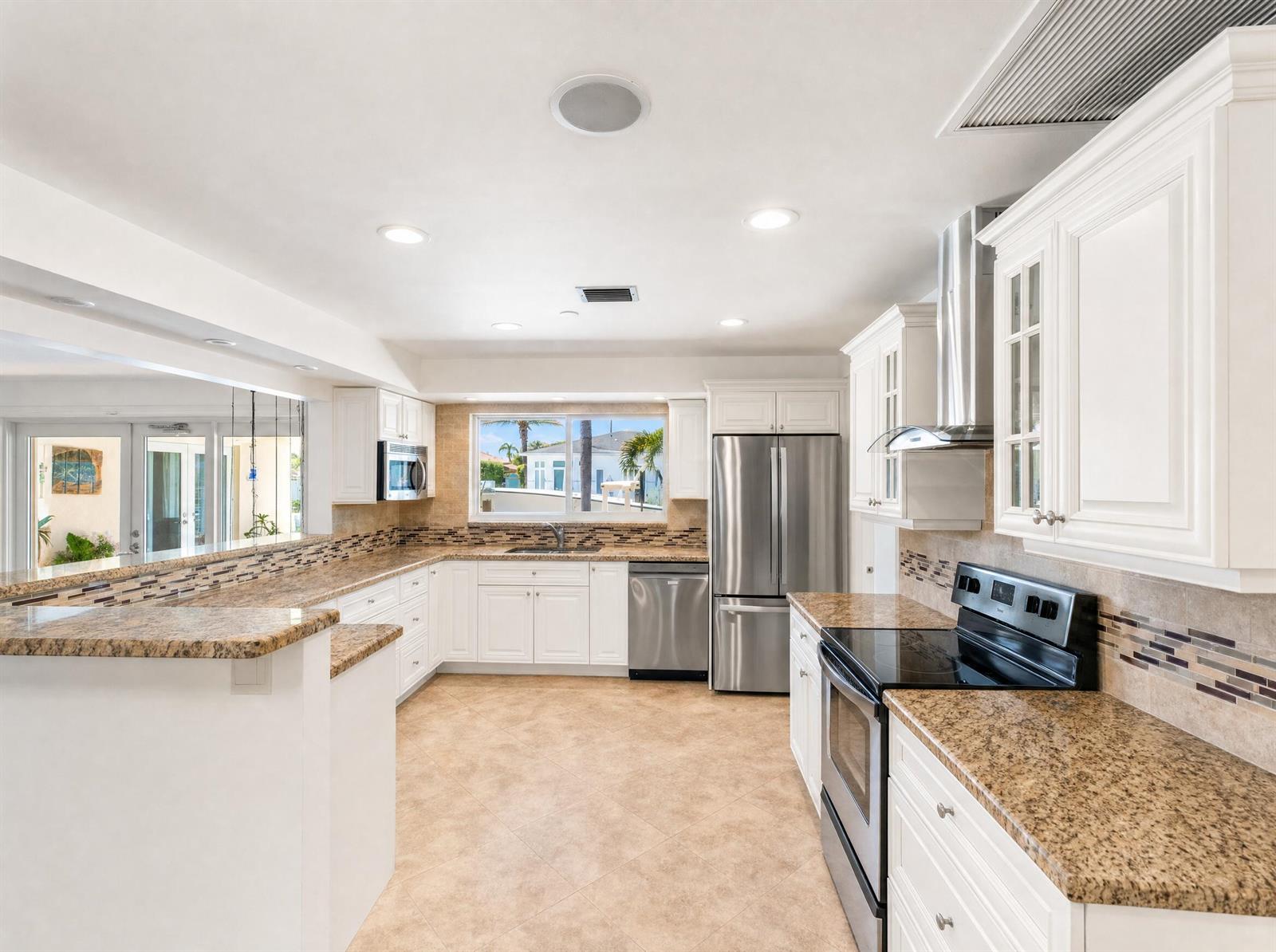 A kitchen features white cabinets, granite countertops, stainless steel appliances, and a tiled backsplash — 330 SE 10th Street, Pompano Beach FL 33060, POMPANO BEACH, FL