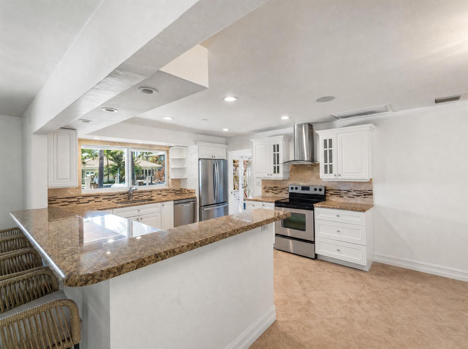 A kitchen features white cabinets, granite countertops, stainless steel appliances, and a breakfast bar — 330 SE 10th Street, Pompano Beach FL 33060, POMPANO BEACH, FL