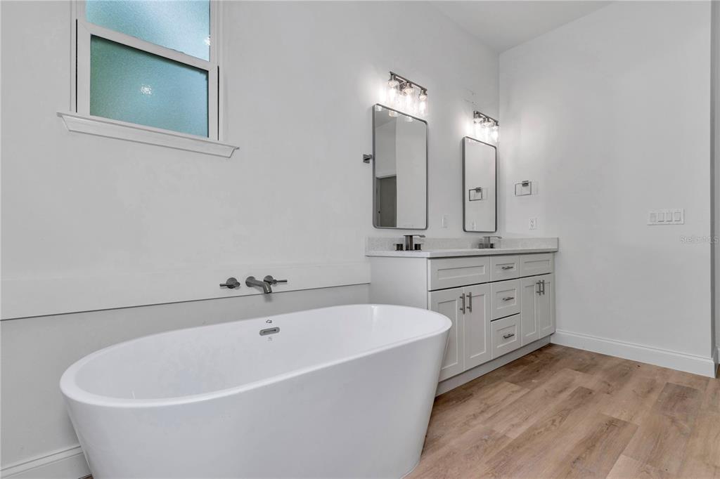 A bathroom features a freestanding white tub, a double vanity, and light wood-look flooring — 7243 N EMBASSY TERRACE, CITRUS SPRINGS, FL
