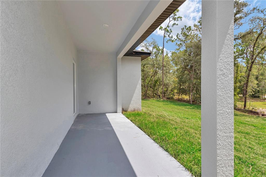 A modern kitchen features white cabinetry, stainless steel appliances, and a wood-slatted kitchen island — 7243 N EMBASSY TERRACE, CITRUS SPRINGS, FL
