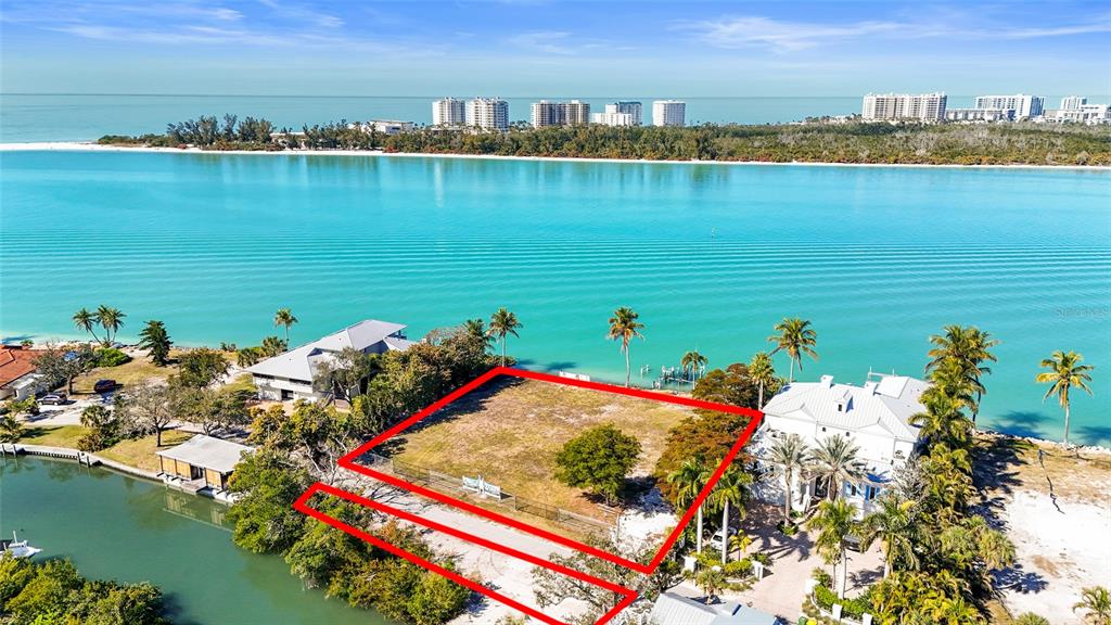 An aerial view shows a vacant waterfront lot outlined in red between two houses — 3550 BAYOU LOUISE LANE, SARASOTA, FL