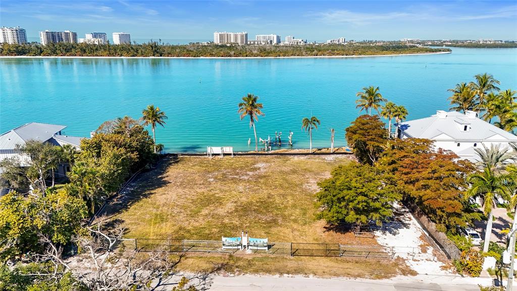 An aerial view of a vacant waterfront lot featuring palm trees and a fenced perimeter — 3550 BAYOU LOUISE LANE, SARASOTA, FL