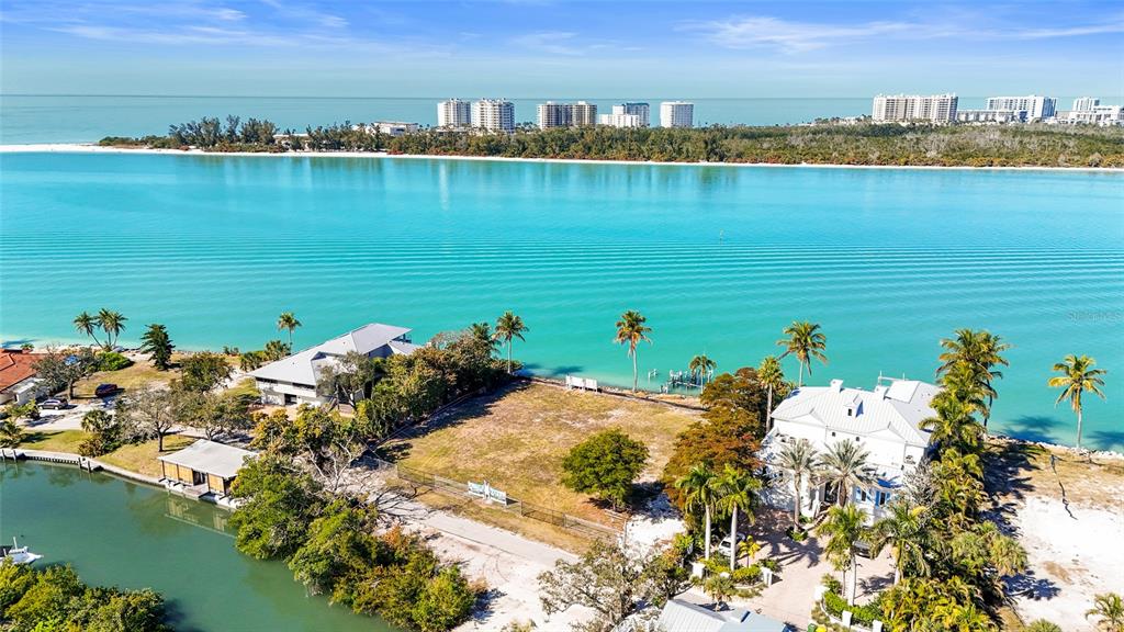 An aerial view shows a vacant waterfront lot situated between two houses near the ocean — 3550 BAYOU LOUISE LANE, SARASOTA, FL