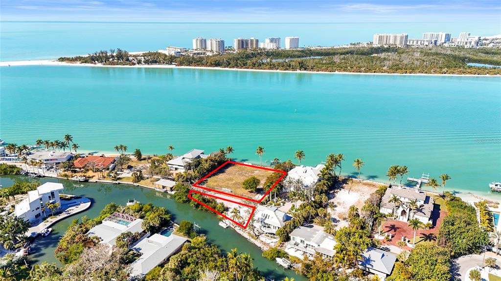 An aerial view shows a vacant waterfront lot outlined in red along a canal — 3550 BAYOU LOUISE LANE, SARASOTA, FL