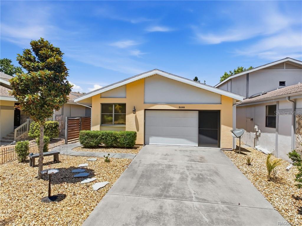 A single-story house with a yellow exterior, a concrete driveway, and a garage — 5198 S RIVERVIEW CIRCLE, HOMOSASSA, FL