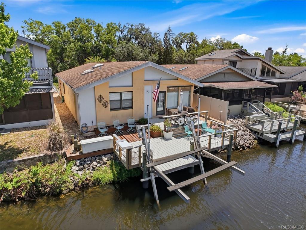 A waterfront house with a wooden deck and boat lift sits along a canal — 5198 S RIVERVIEW CIRCLE, HOMOSASSA, FL
