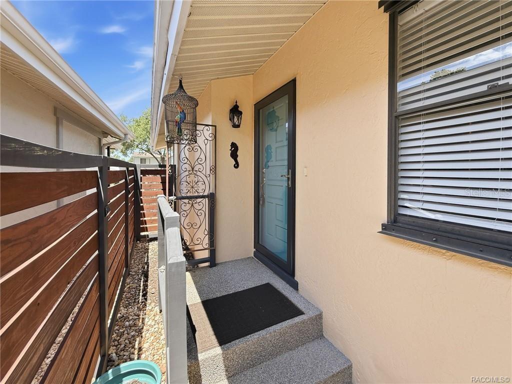 A front entryway with a screen door, a decorative metal screen, and a wooden fence — 5198 S RIVERVIEW CIRCLE, HOMOSASSA, FL