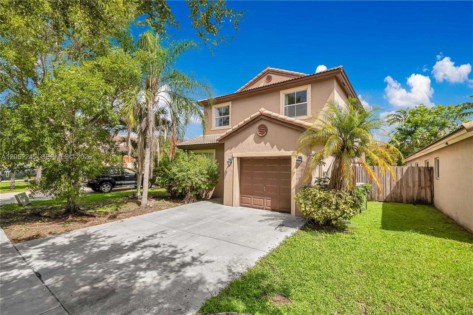 A two-story tan house with a single-car garage and a concrete driveway — 2019 SE 13th St, Homestead FL 33035, HOMESTEAD, FL