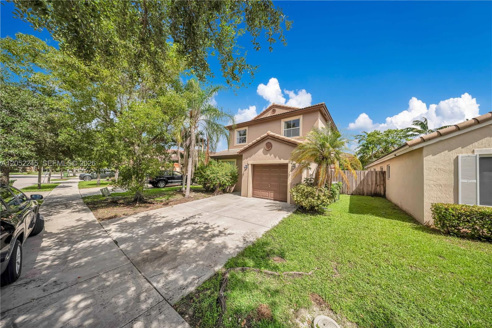 A two-story tan house with a brown garage door and a concrete driveway — 2019 SE 13th St, Homestead FL 33035, HOMESTEAD, FL