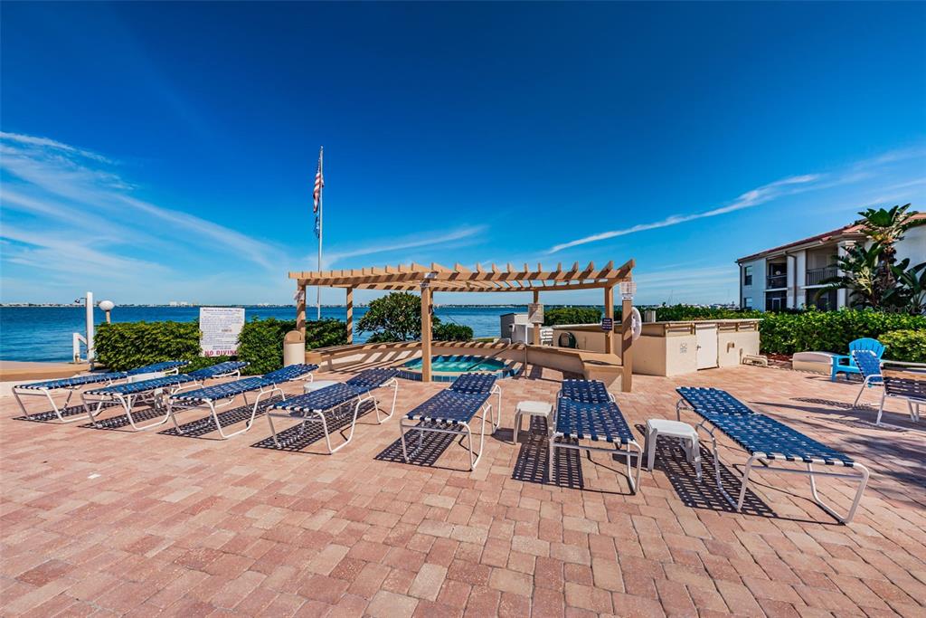 A patio area features lounge chairs, a pergola, and a hot tub overlooking the water — 6145 SUN BOULEVARD UNIT 607, ST PETERSBURG, FL
