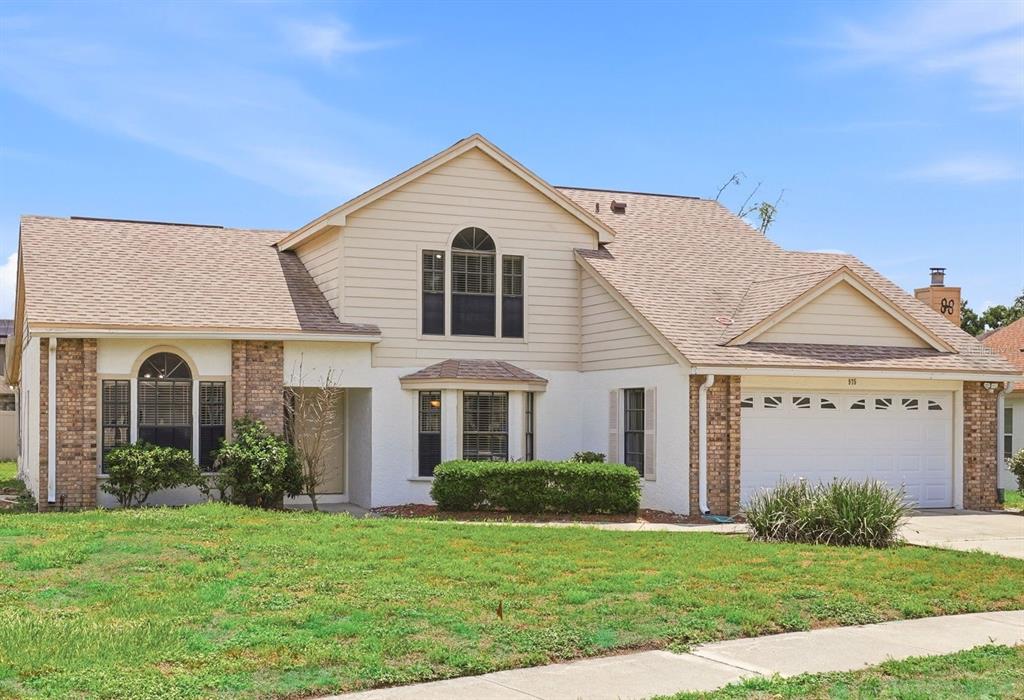 A two-story suburban house with a tan siding, white stucco, and brick exterior — 975 CROSS CUT WAY, LONGWOOD, FL