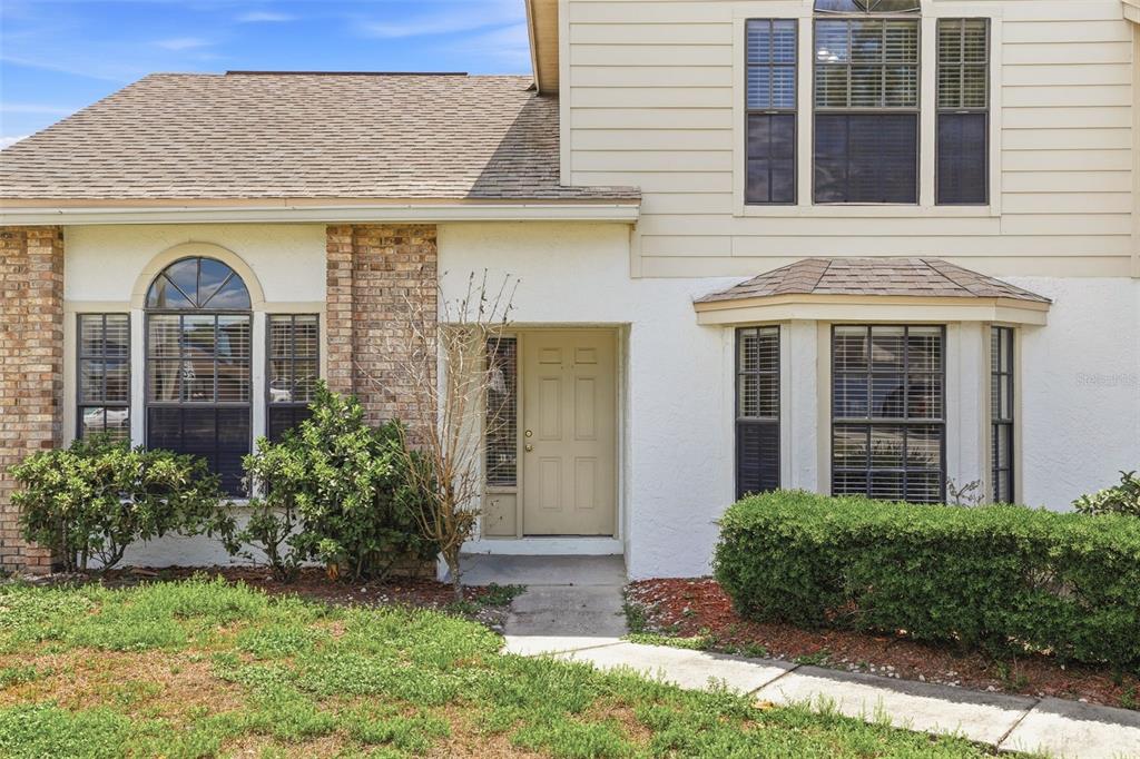 The exterior of a two-story house features a tan door, brick accents, and bay windows — 975 CROSS CUT WAY, LONGWOOD, FL