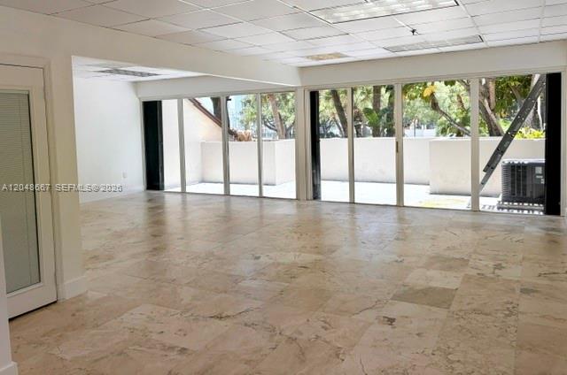 An empty room with beige tile flooring, a drop ceiling, and large sliding glass doors — 520 Brickell Key Dr # O208, Miami FL 33131, MIAMI, FL