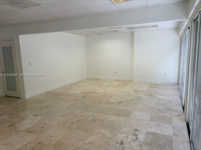 An empty room features light-colored stone tile flooring, white walls, and a drop ceiling — 520 Brickell Key Dr # O208, Miami FL 33131, MIAMI, FL