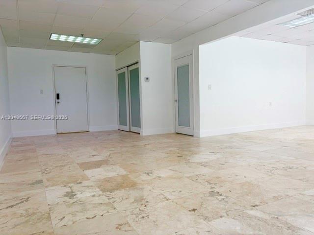 An interior room features white walls, a drop ceiling, and light-colored stone tile flooring — 520 Brickell Key Dr # O208, Miami FL 33131, MIAMI, FL